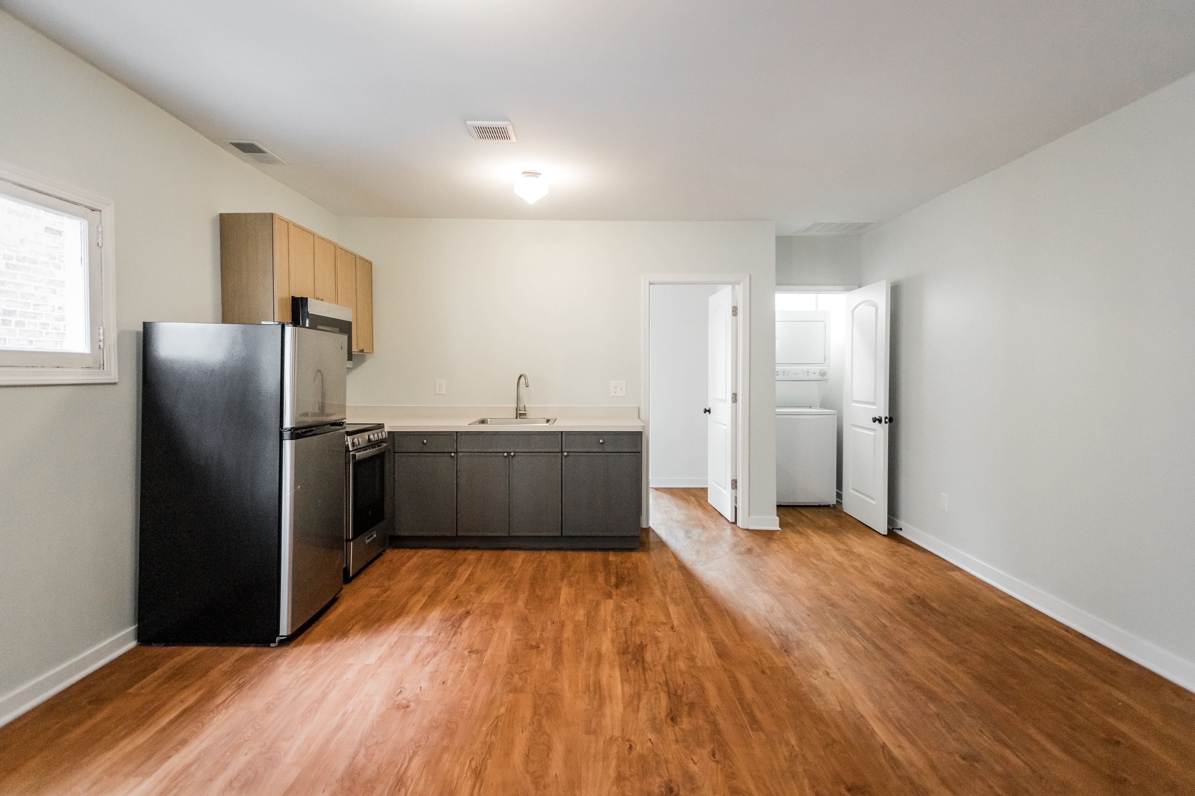 A kitchen with a black fridge and wooden floors.